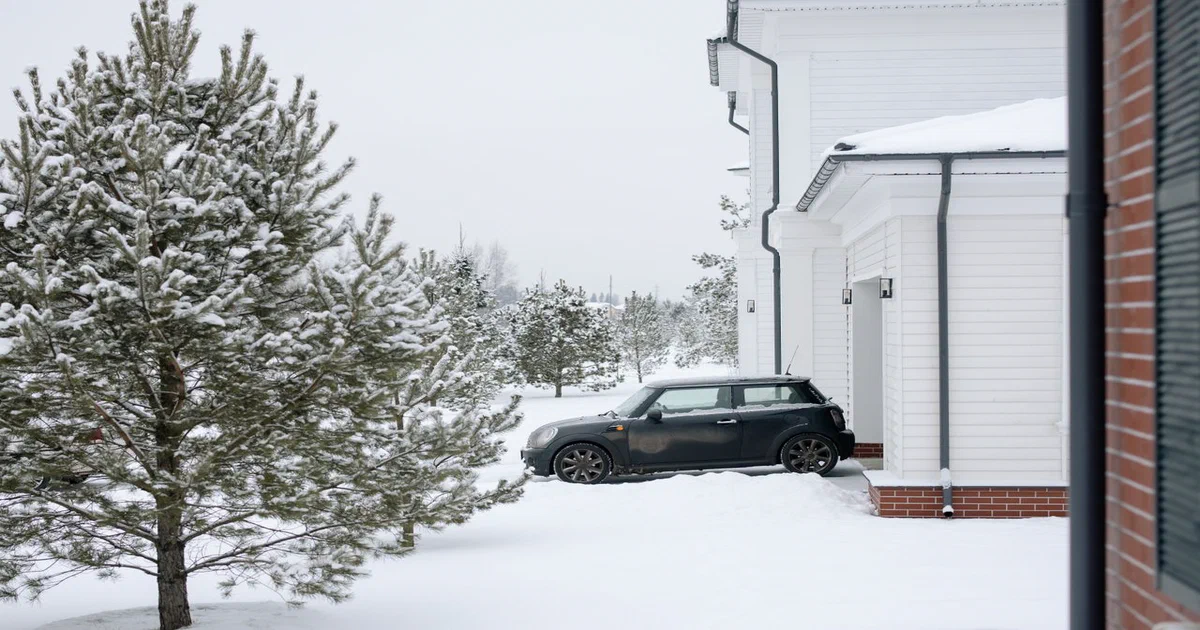 Voiture stationnée dans une entrée enneigée devant une maison